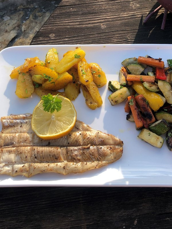 Forellenfilet mit Zitrone neben Kartoffeln und Gemüse