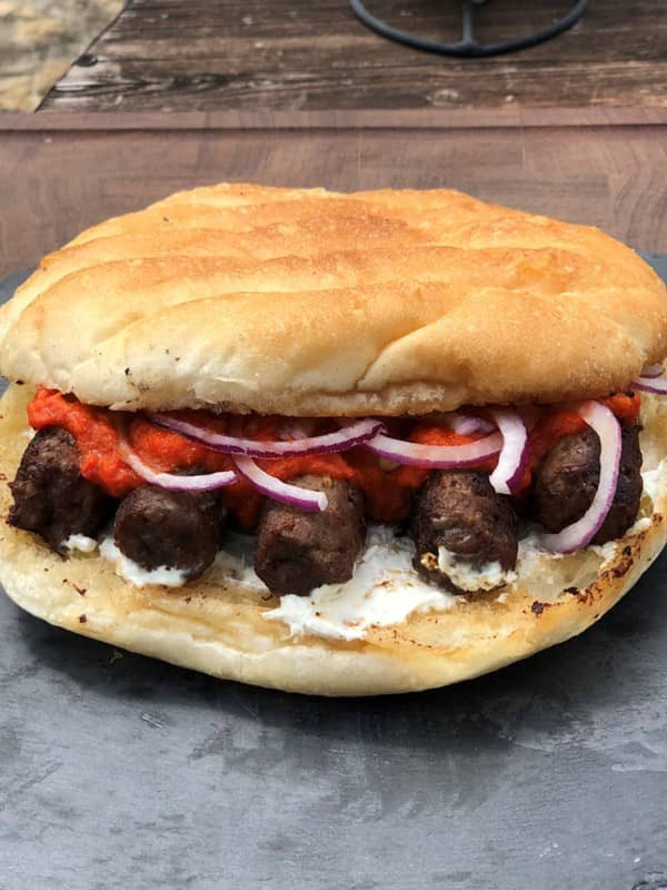 Ćevapčići im Fladenbrot mit Zwiebeln, Schmand und Ajvar